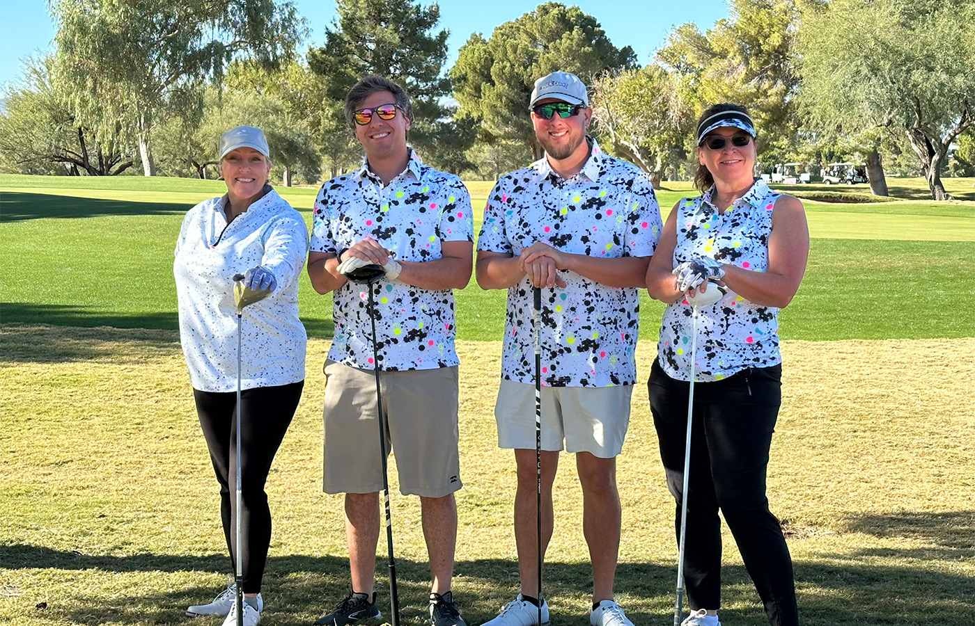 People standing on a golf course smiling.