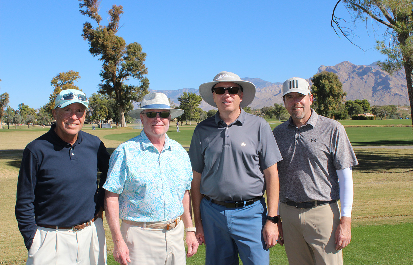 People standing on a golf course smiling.