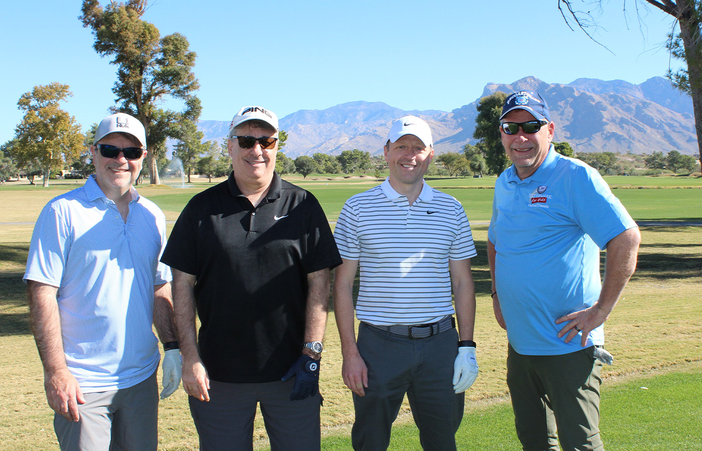 People standing on a golf course smiling.