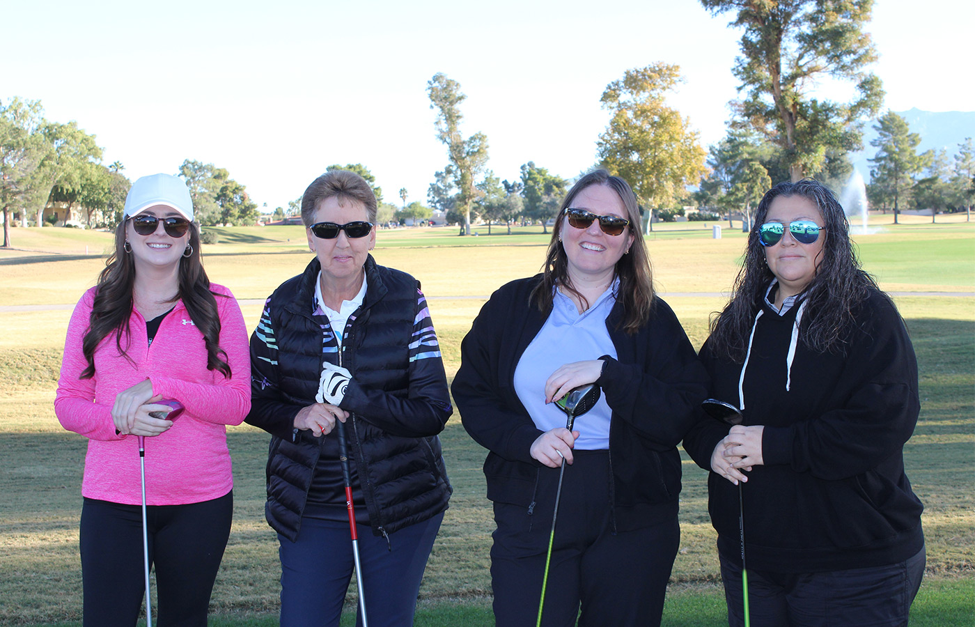 People standing on a golf course smiling.