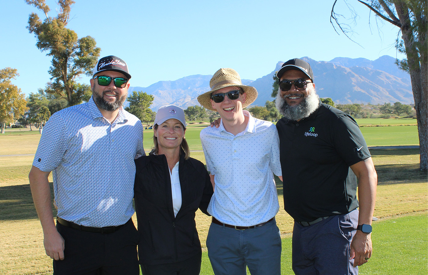 People standing on a golf course smiling.