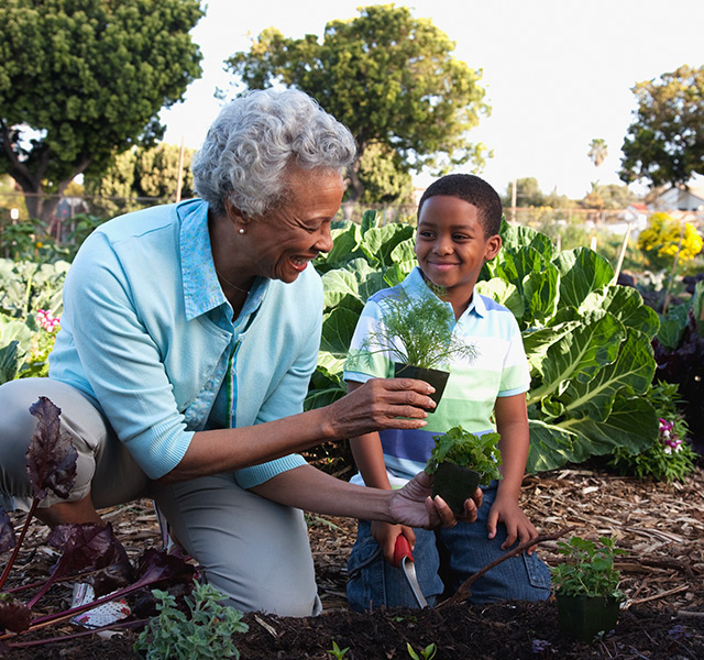 An adult helping a child in the garden.