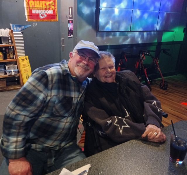 Two people sitting at table in a restaurant smiling at the camera.