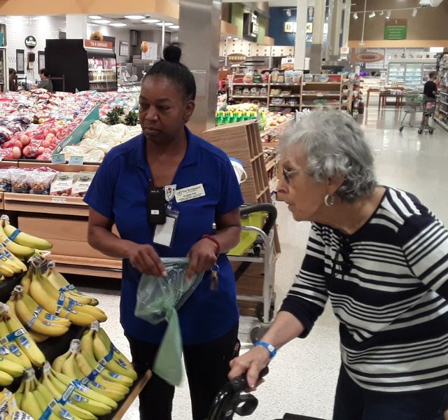 Resident and associate choosing bananas at grocery store.