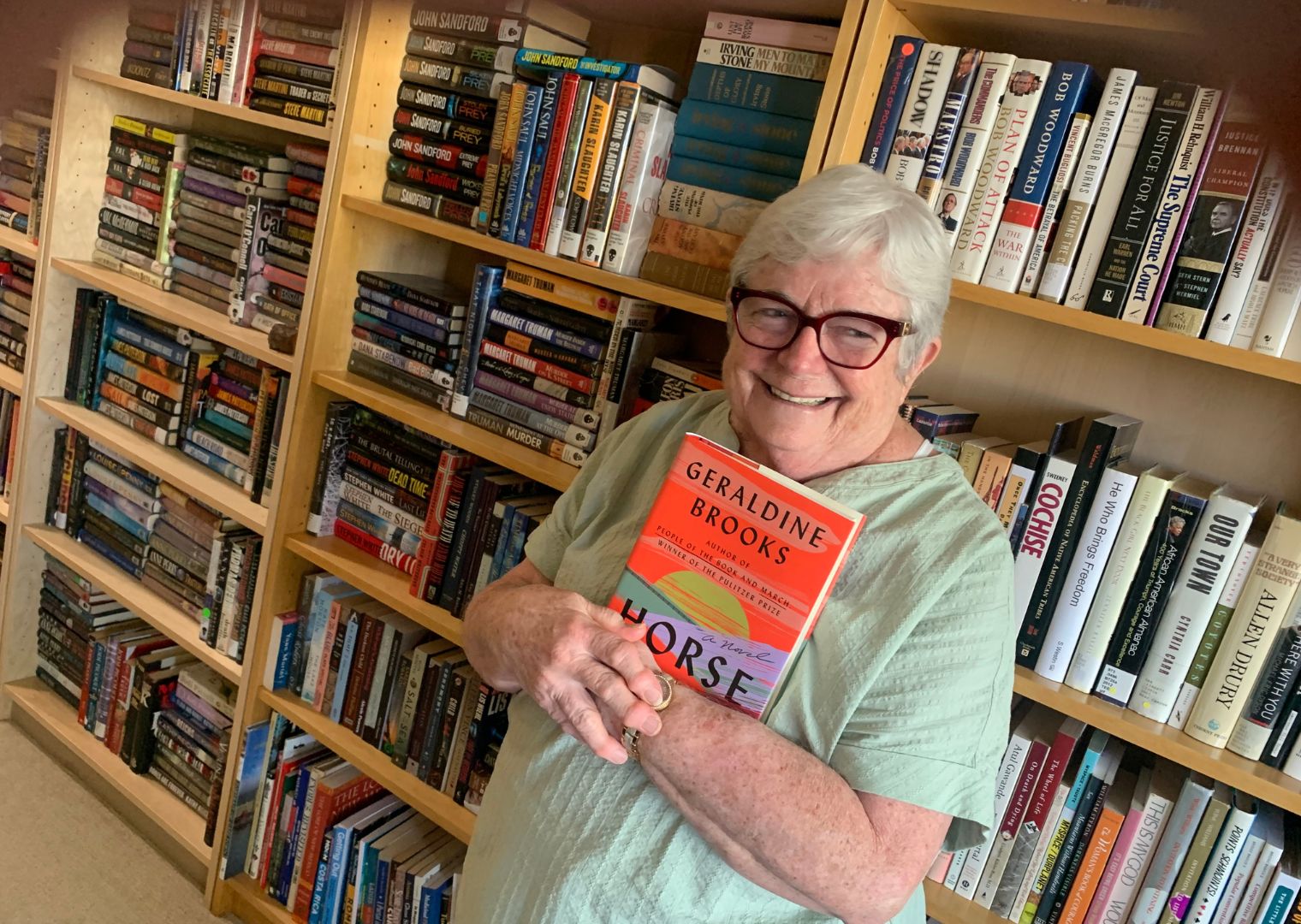 Woman holding book in front of bookcase.