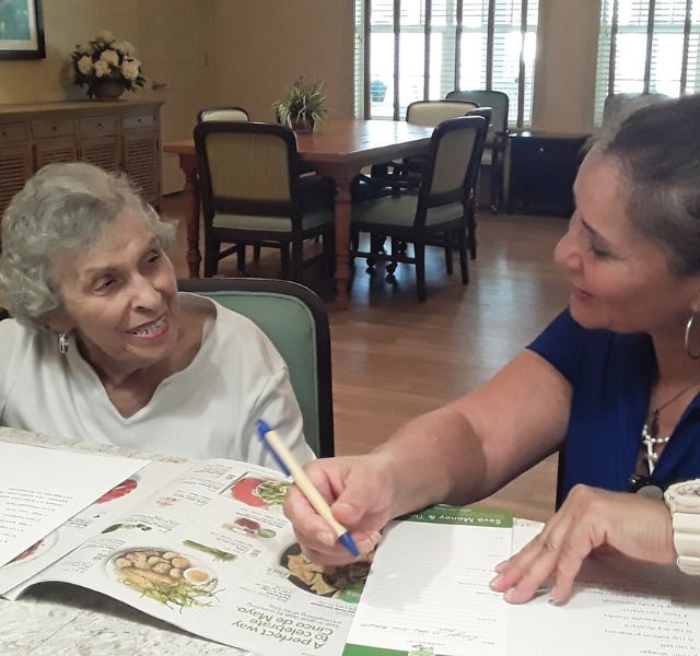 Resident and associate sitting at table writing a grocery list.