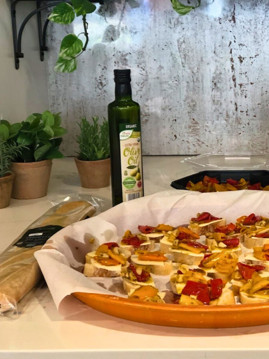 A dish of sliced baguette with cheese, tomato, and olive oil on top.