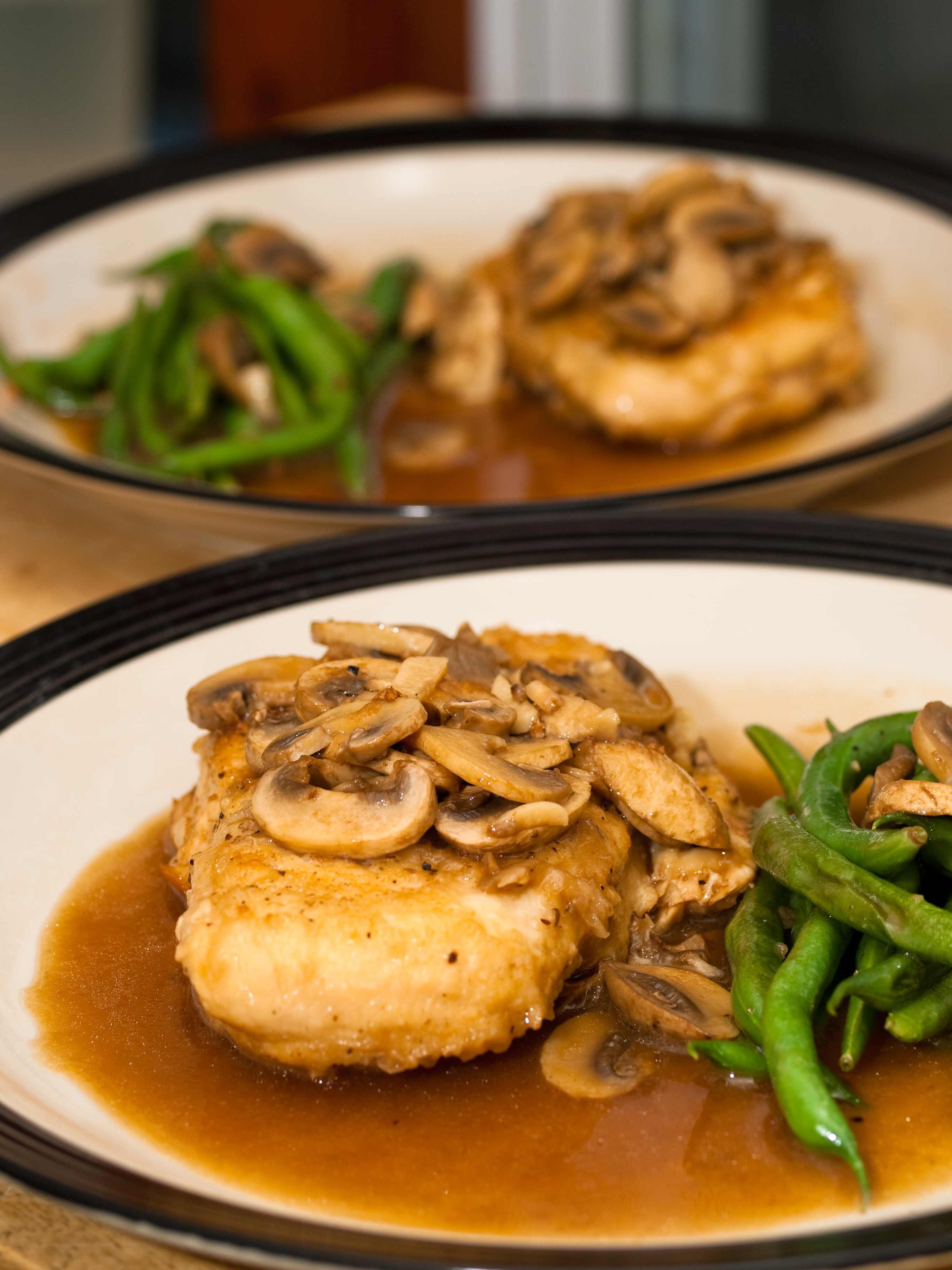 A mushroom chicken dish with green beans on the side.