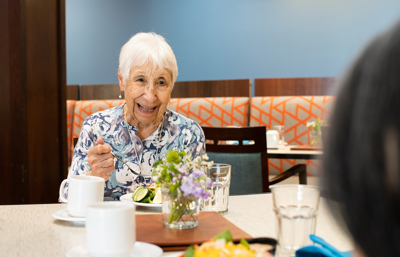 A resident is having dinner in a dining area at a community.