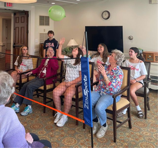 Residents and students playing volleyball with a balloon.