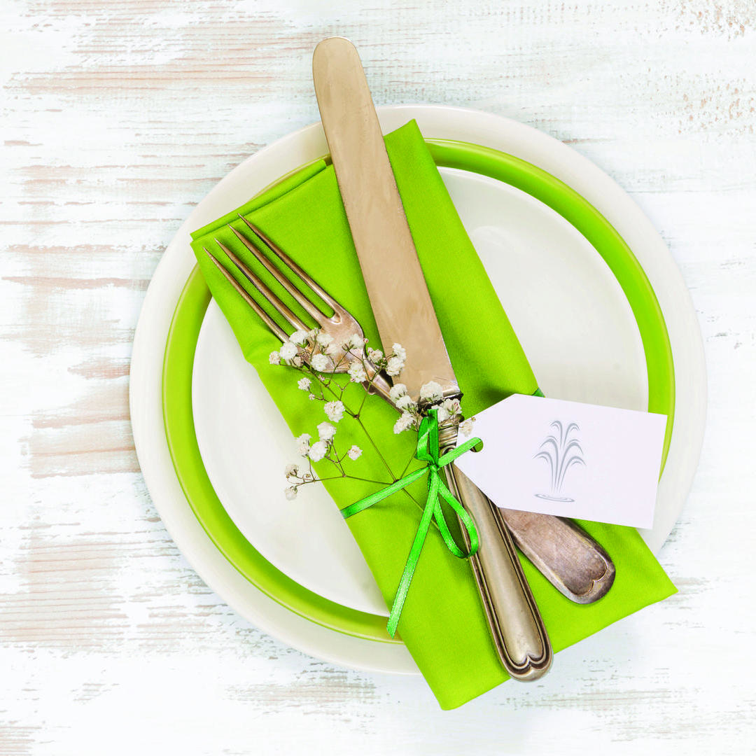 Table setting with white and green plates and silverware.