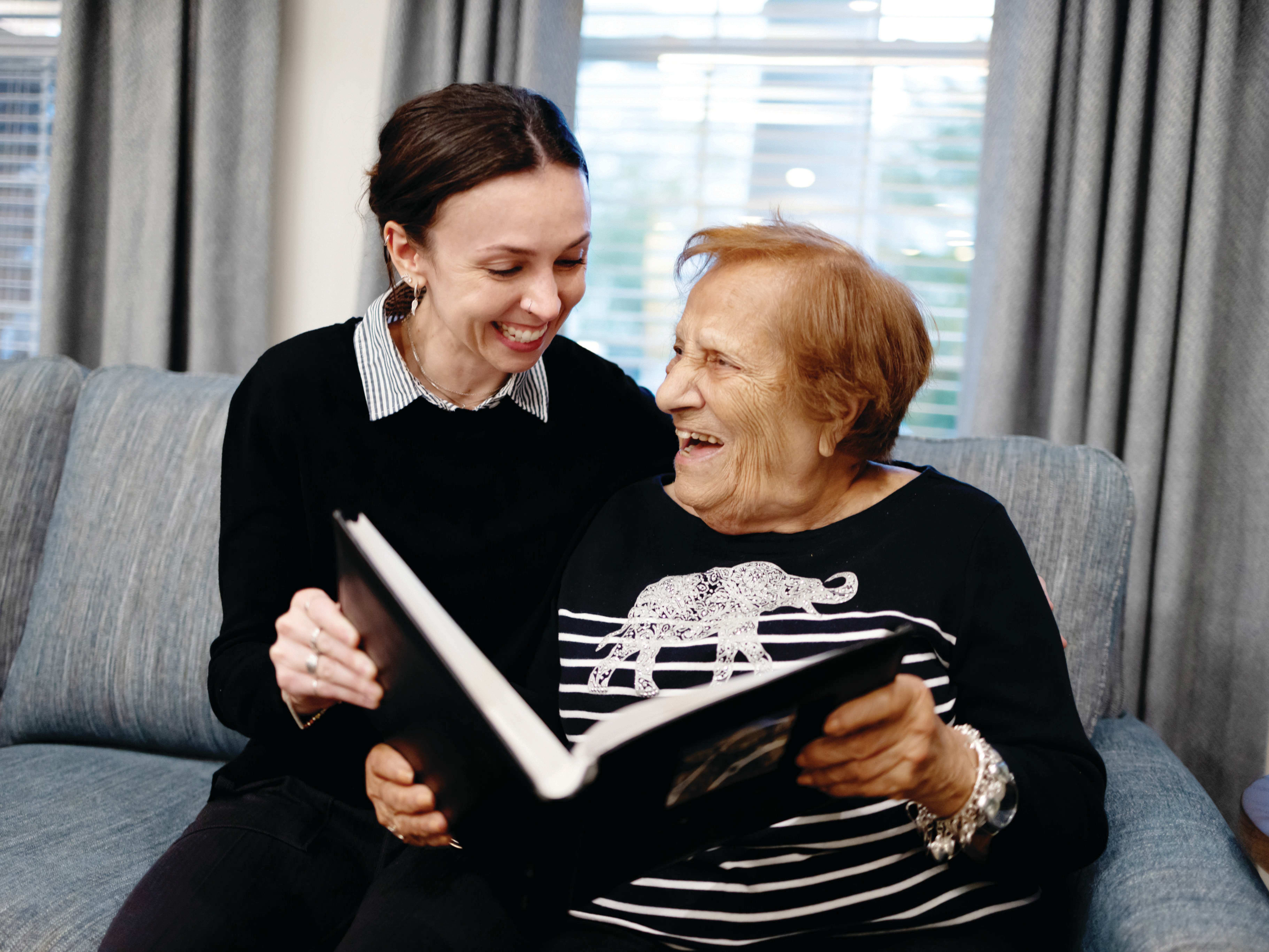 Two happy adults on couch looking at photo album