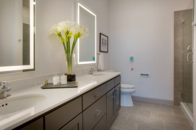 Bathroom with long white counter and toilet and modern shower at The Hacienda at Georgetown.