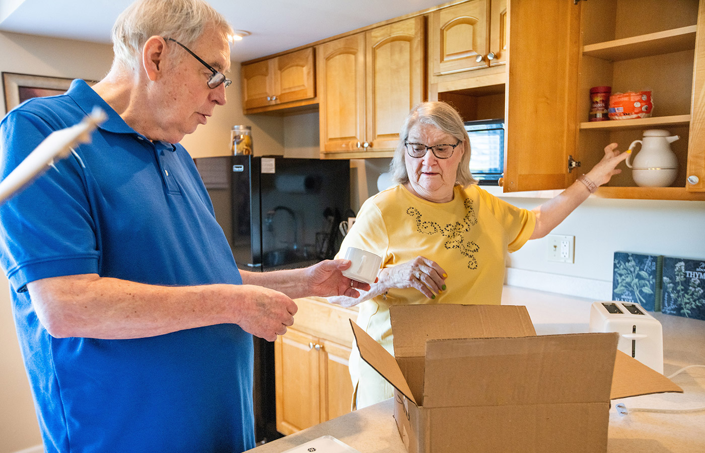 Two people are packing up their kitchen.