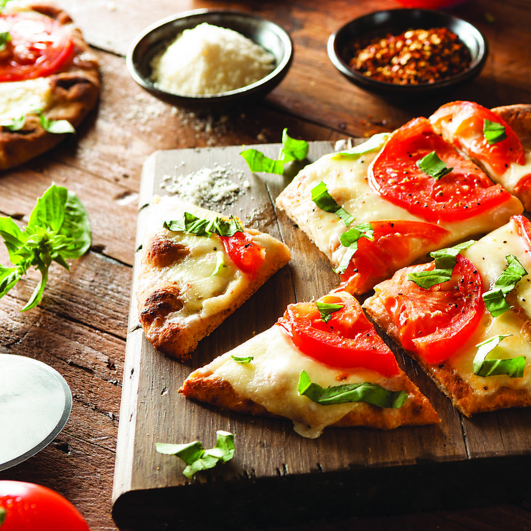 Margarita pizza on wooden cutting board.