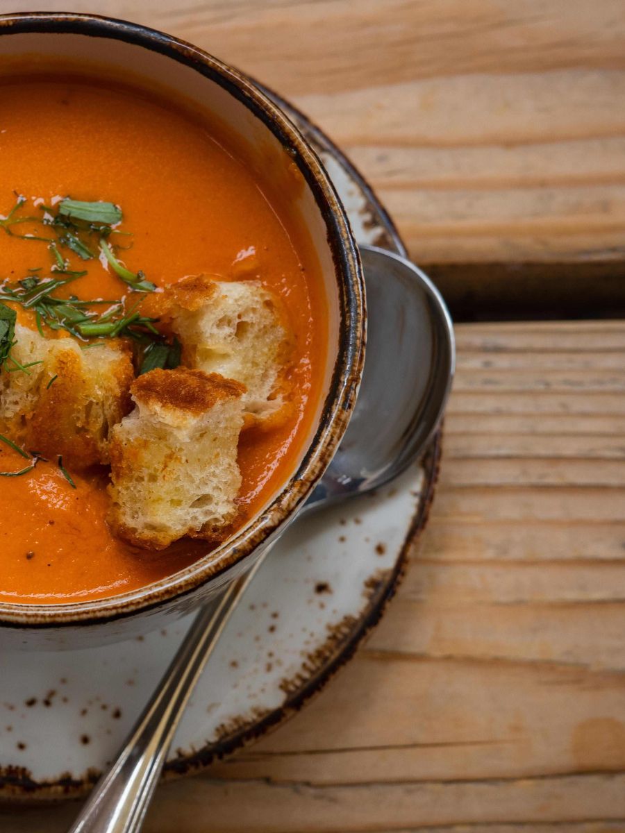 A bowl of tomato basil soup topped with croutons.