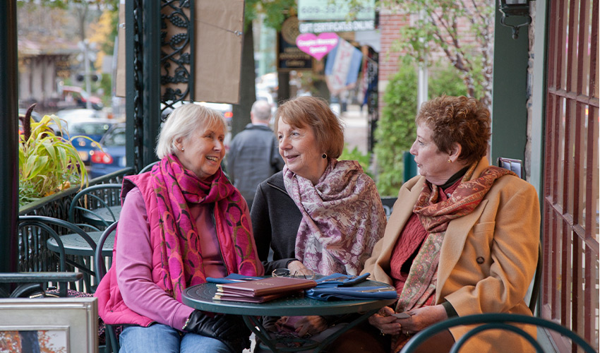 Three friends sitting outside at a table.