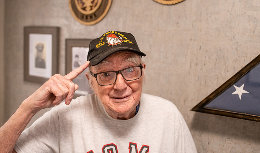 A senior man pointing to his veteran hat.