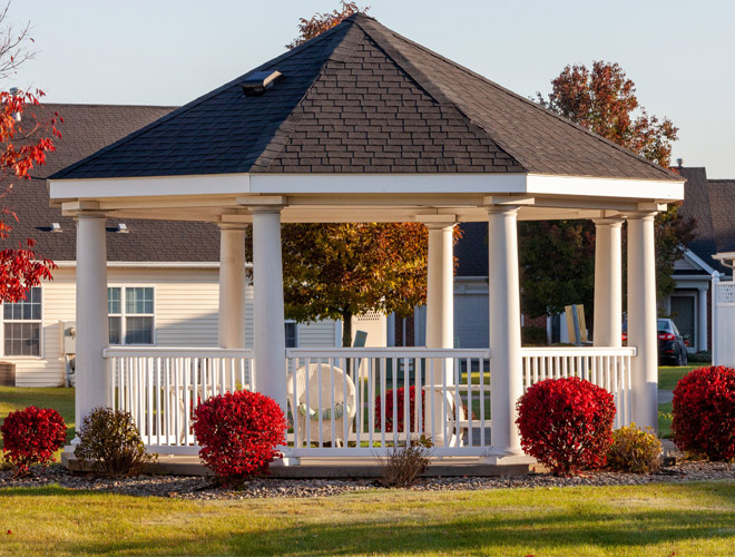 Gazebo surrounded by bushes and flowers.