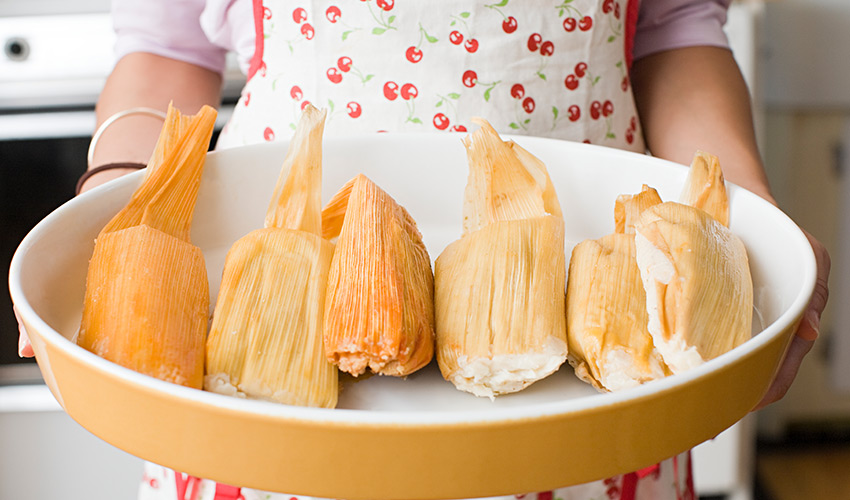 A person holding a dish of tamales.