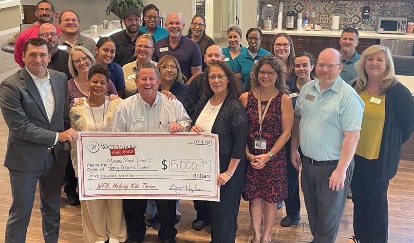 A group of people holding a large donation check.